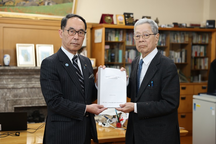 藤野委員長より、委員会の最終報告書を受け取る様子