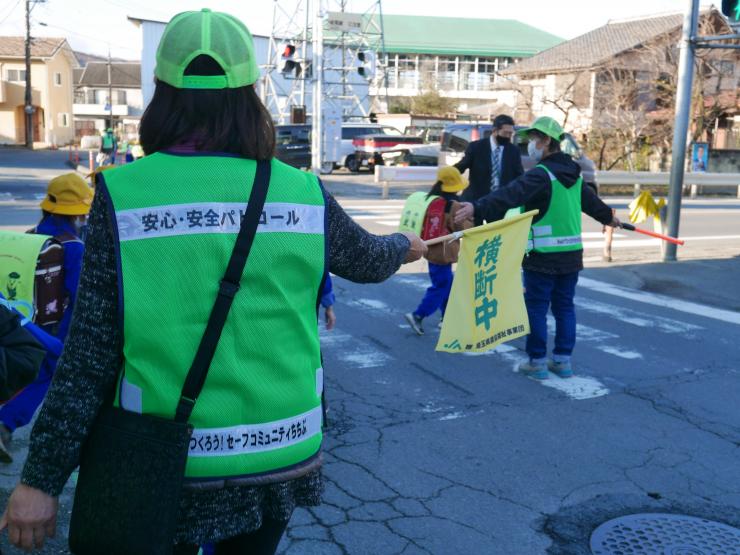 横断歩道で旗を振る見守り隊員