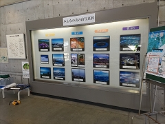 ガラスの展示スペースに飾られた様々な表情の美の山の写真たち