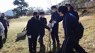 高校生5名が苗木を支えながら談笑している。