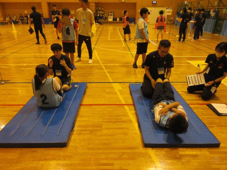 体育館で複数の参加者が並んで上体起こしに挑戦している様子