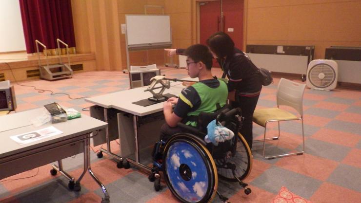 屋内の射撃用スペースで車いすの参加者が的を見据える様子