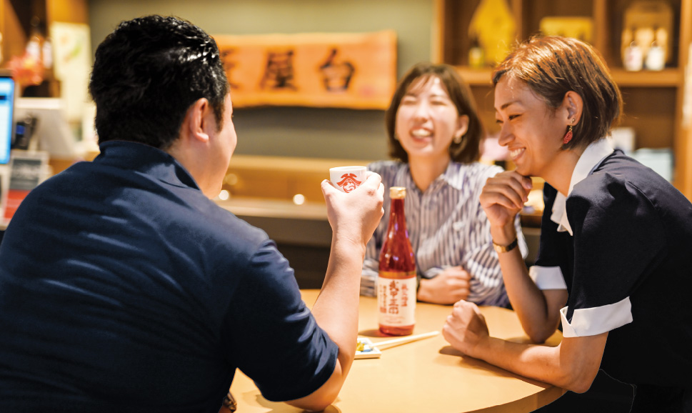 西武秩父駅前温泉 祭の湯にある角打ちスペース「酒匠屋台」でお酒を飲みながら談笑している男女の写真