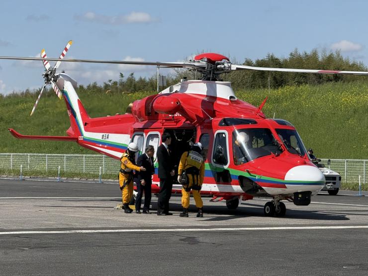 ヘリコプターの中の様子を見る飯塚俊彦副議長