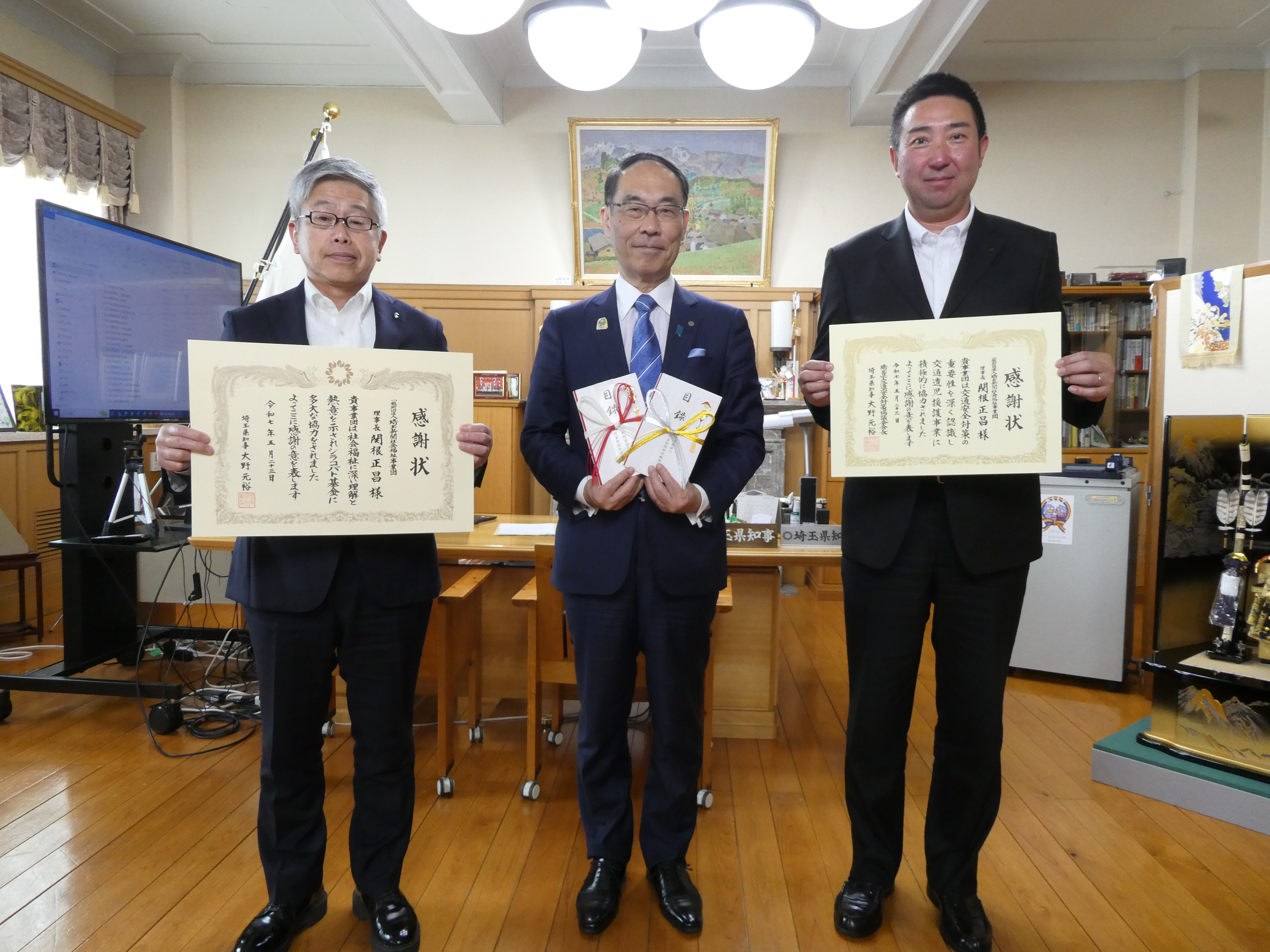 感謝状贈呈式で表彰者（一般財団法人埼玉新聞社会福祉事業団）と記念写真を撮る知事の写真