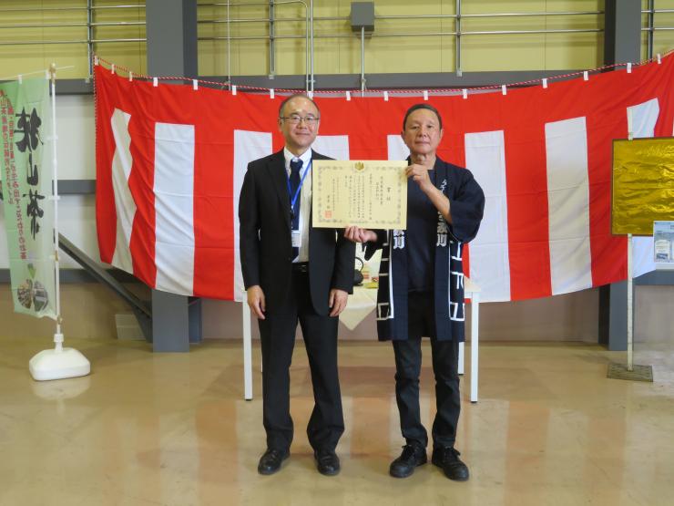 賞状を掲げる代表取締役