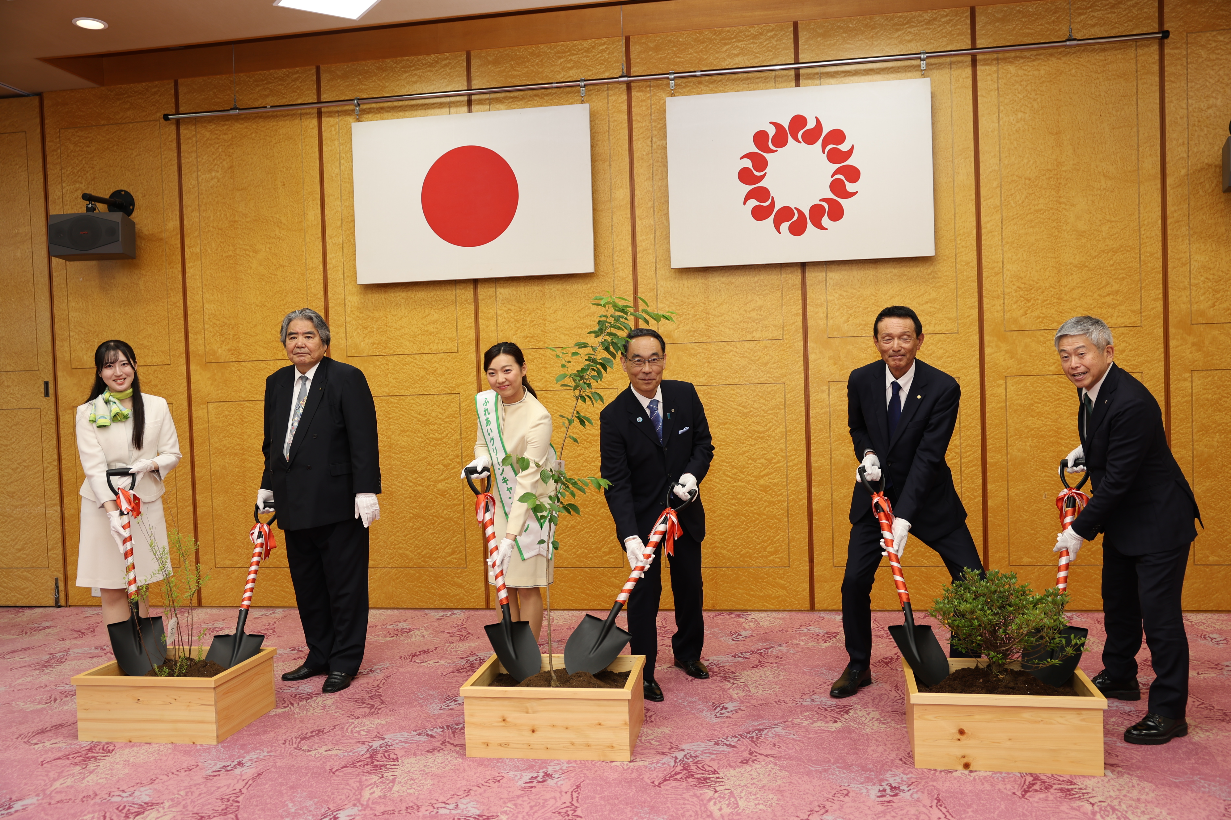 感謝状贈呈式で表彰者（埼玉トヨペット株式会社）と植樹するポーズをとりながら、記念写真を撮る知事の写真