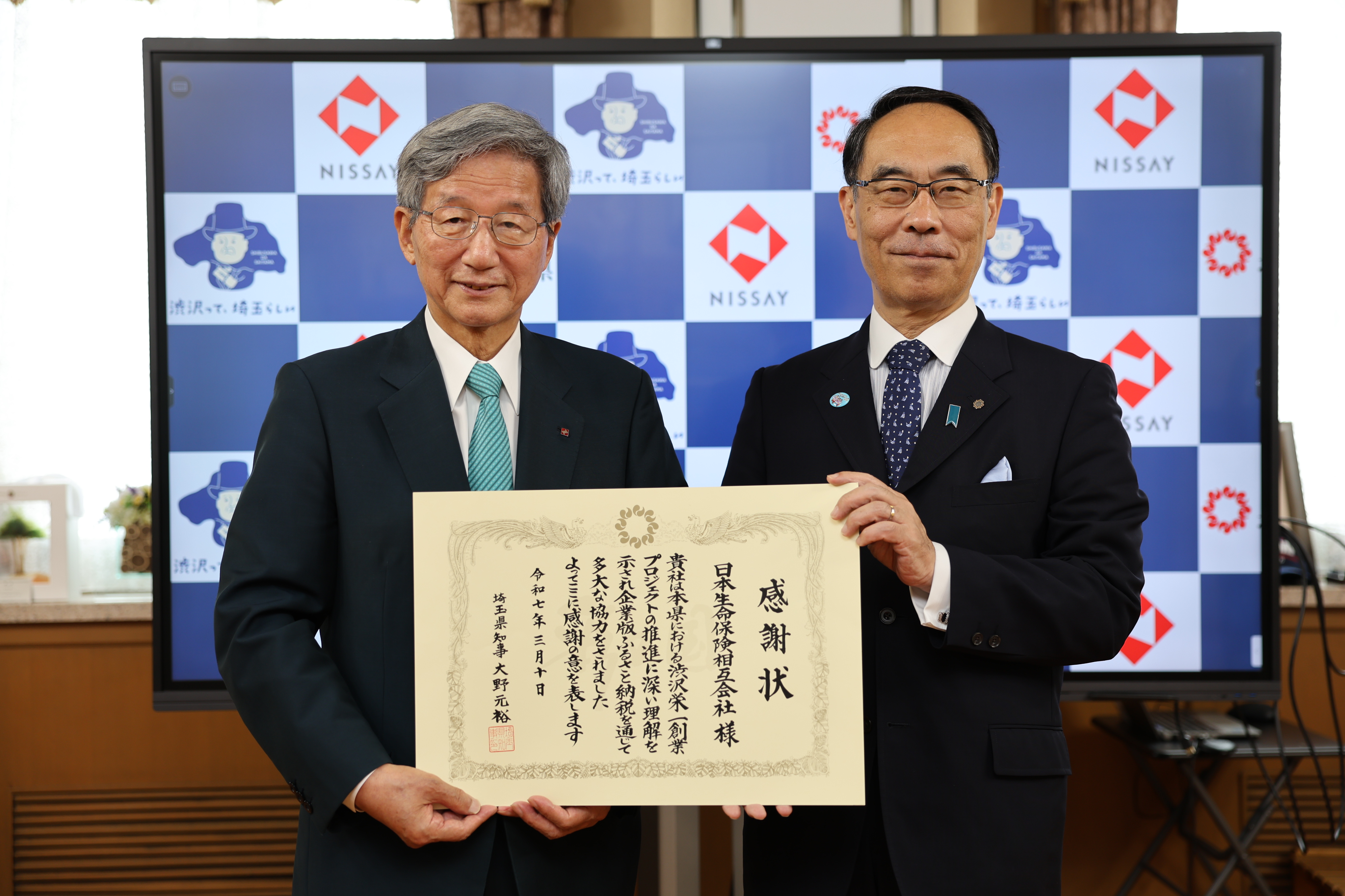 感謝状贈呈式で表彰者（日本生命保険相互会社）と記念写真を撮る知事の写真