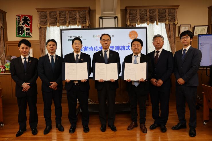 締結式で訪問者と記念写真を撮る知事の写真