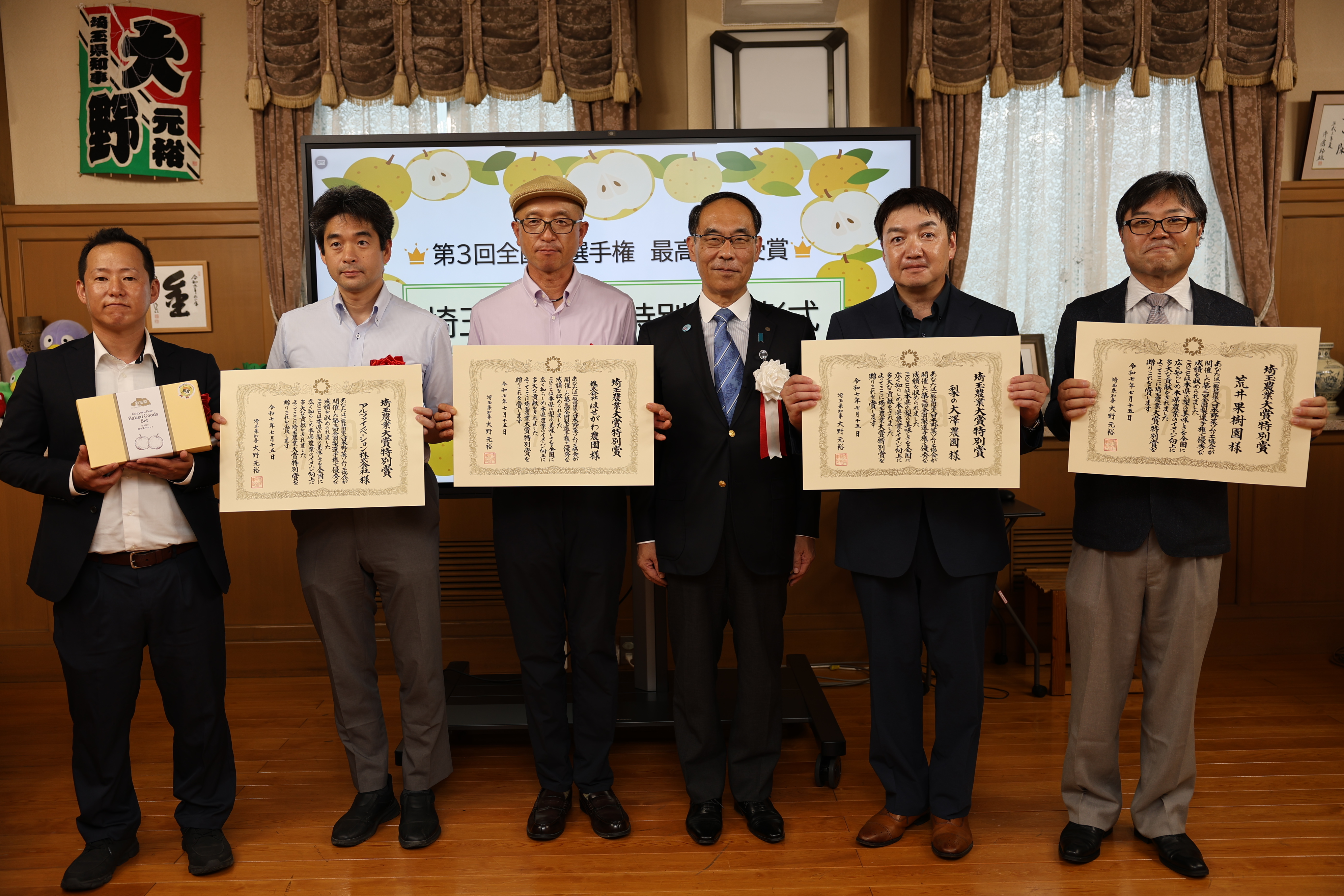 表彰式で受賞者と集合写真を撮る知事の写真