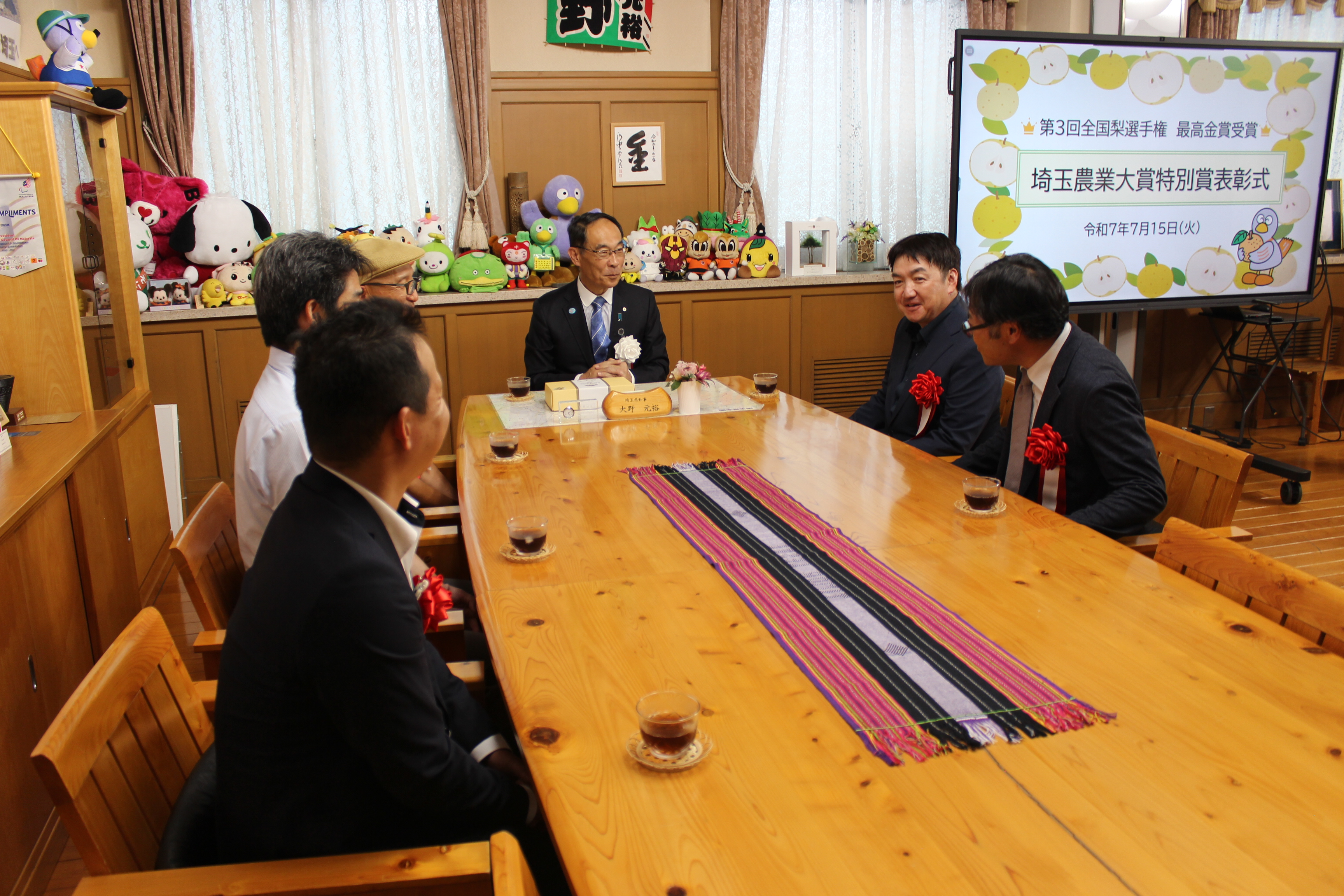 表彰式で受賞者と歓談する知事の写真