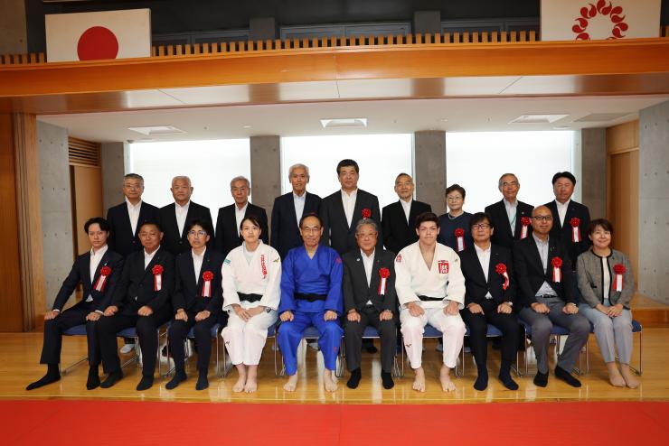 記念式典でオリンピックメダリストらとともに記念写真を撮る知事の写真