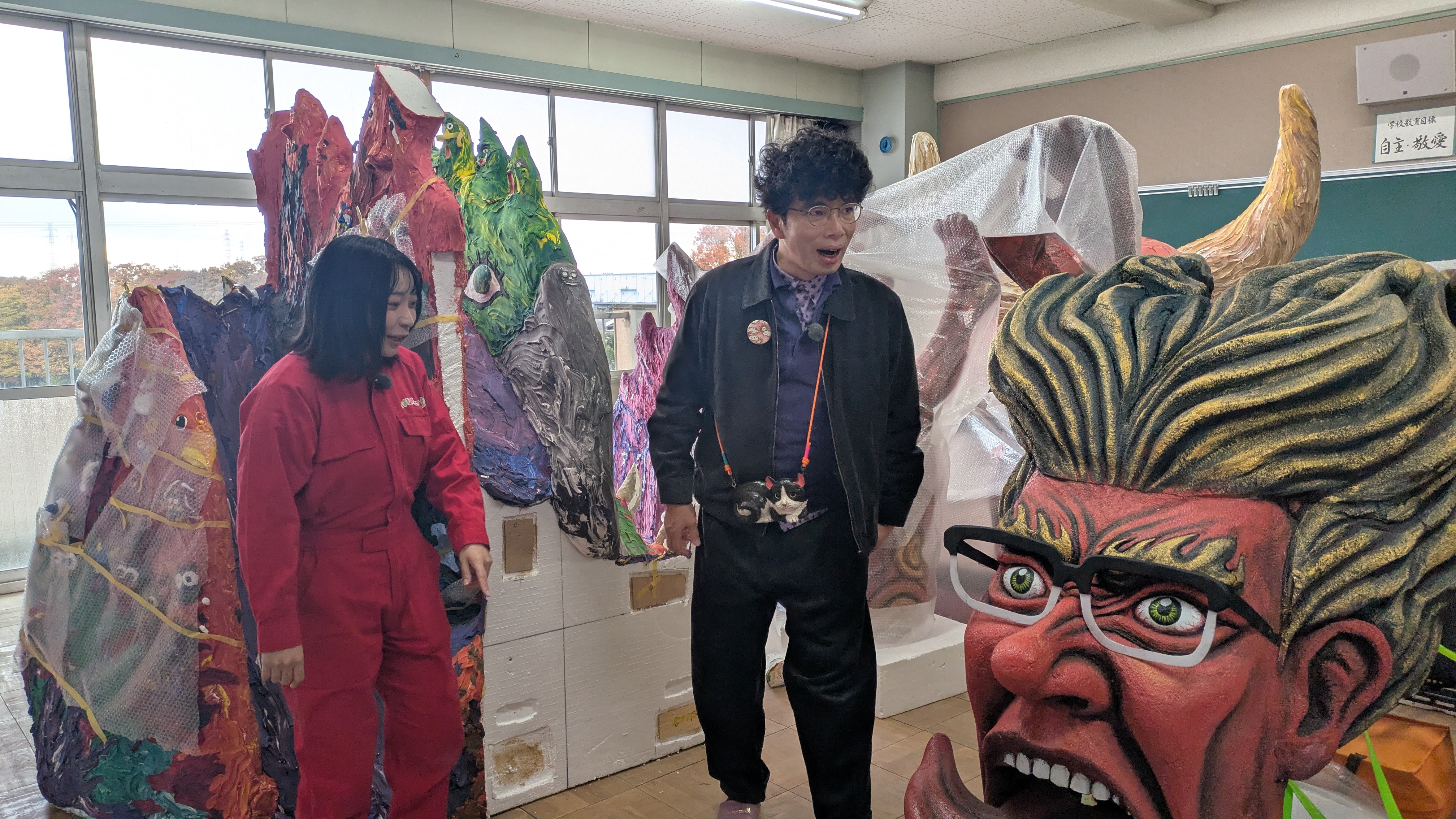 公園魔の前で解説をする片桐仁とそれを聞くアンゴラ村長