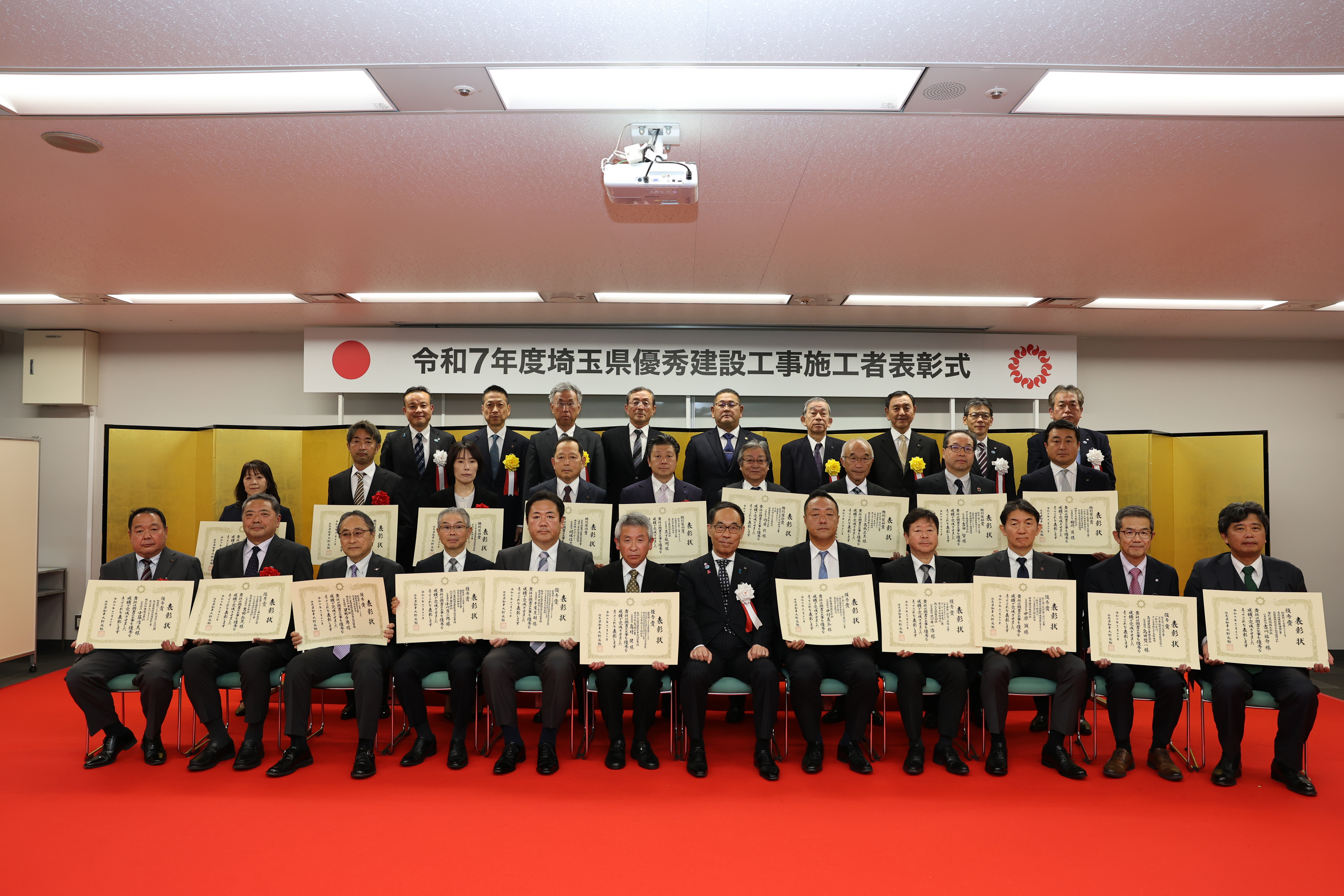 表彰された企業の関係者らと集合写真を撮る知事の写真