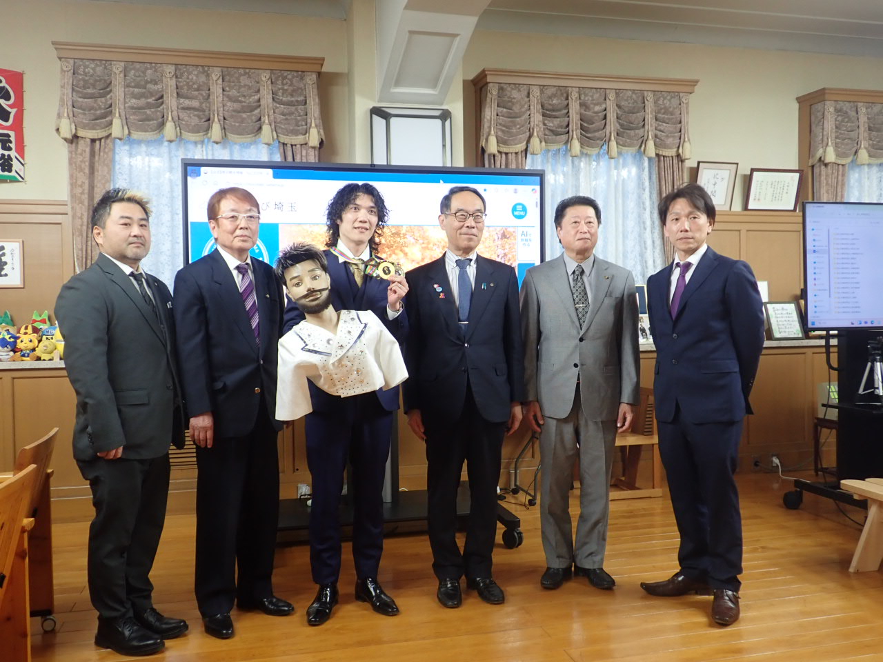 訪問者と記念写真に映る知事の写真