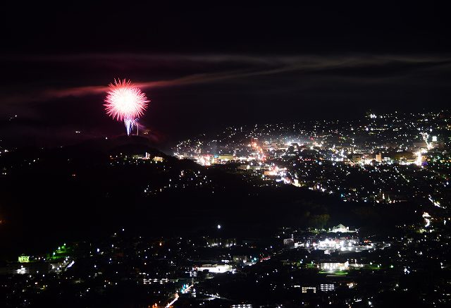 美の山公園から見た秩父夜祭の花火と夜景。引きで見た朱色の花火が夜景とともに映っている。